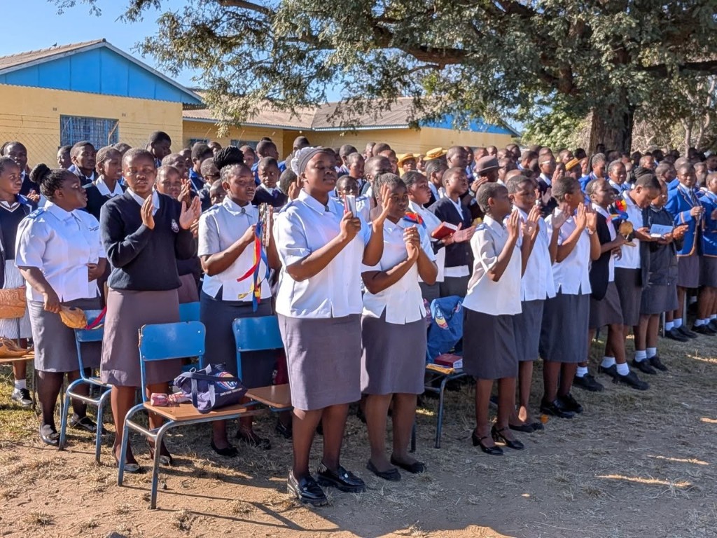 Usher students worshipping outdoors with hymn books and timbrels